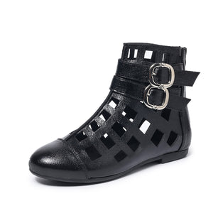 Black ankle boots with cutout design and double buckle straps.