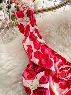 Charming floral ruffle trim mini dress with bow detail in pink and red roses.