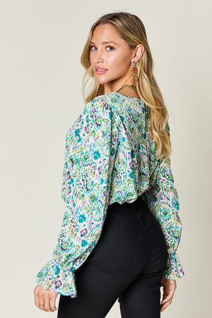 Painterly print blouse with gathered sleeves in abstract blue and green pattern.