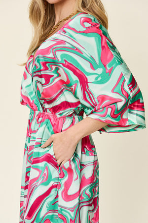 Green swirl print kimono sleeve jumpsuit with elastic waist and pockets.