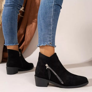 Black suede ankle boots with side zipper and block heel, styled with distressed jeans.
