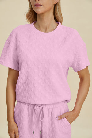 Pink textured knit loungewear set with wide leg pants and short sleeve top.