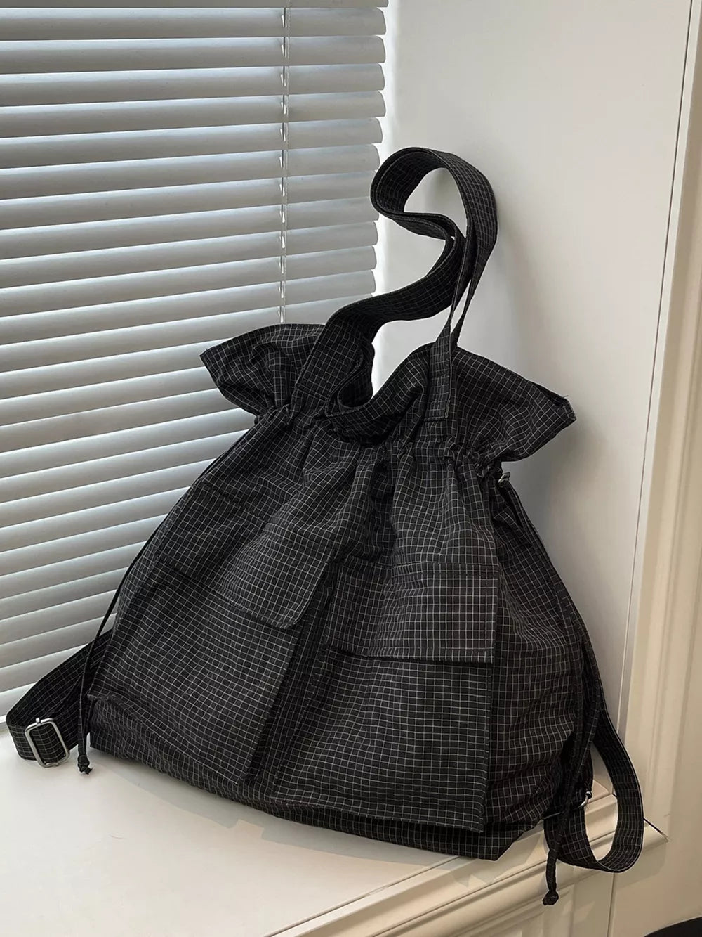 Chic plaid drawstring backpack in grey with multiple pockets and adjustable straps.