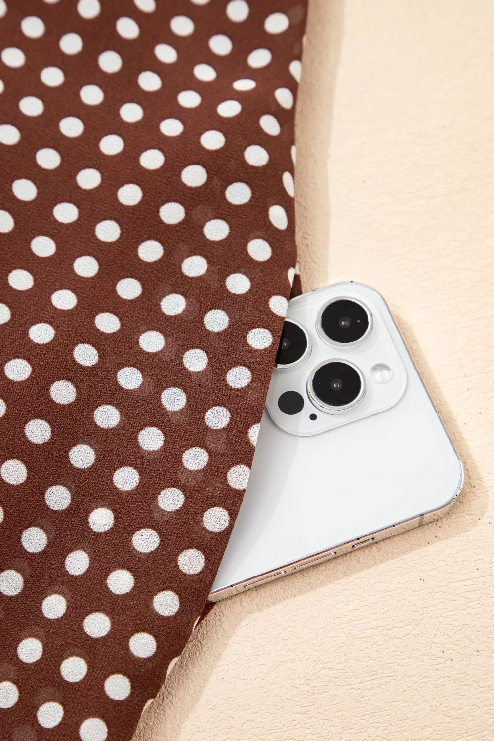 Brown polka dot maxi dress fabric detail with a white phone