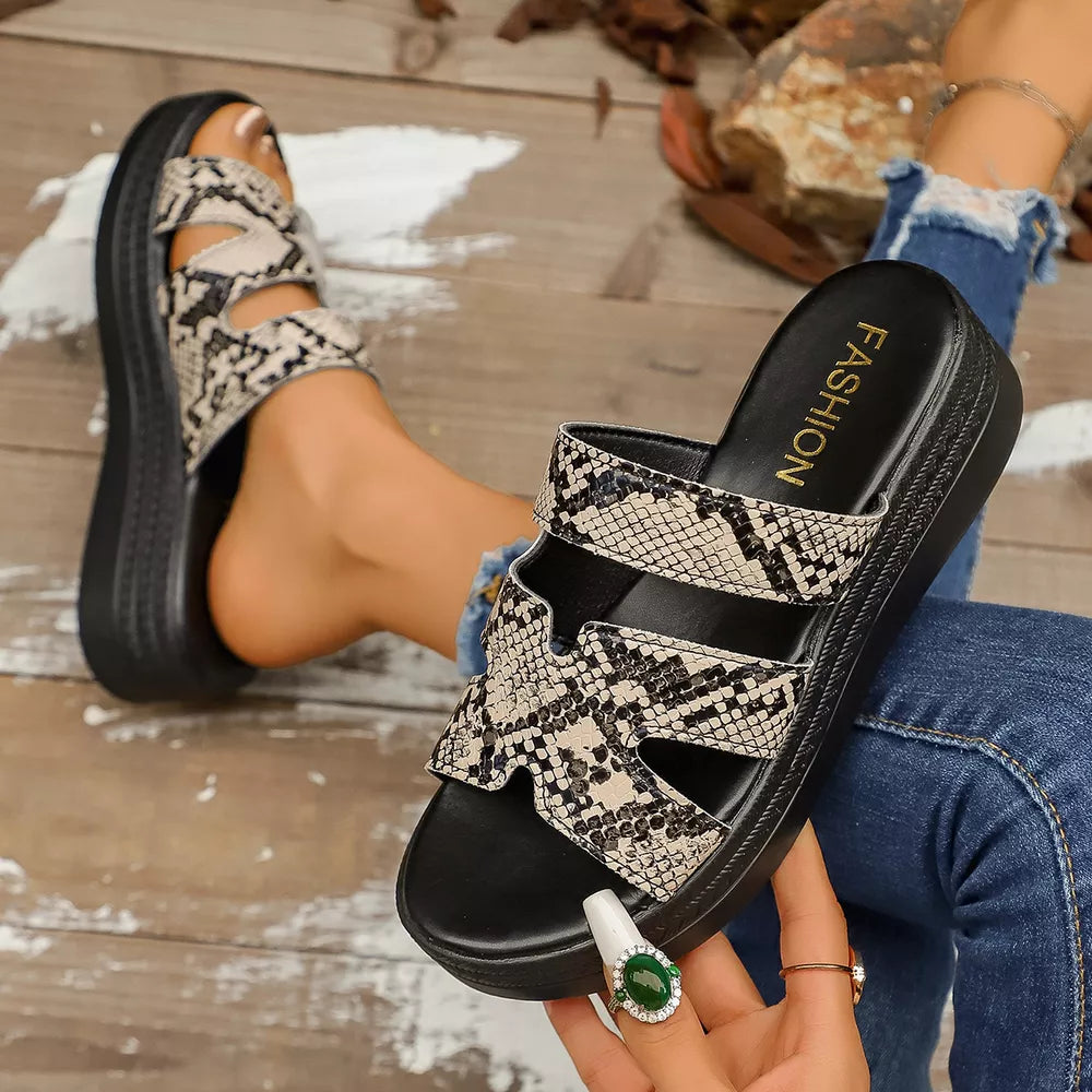 Snakeskin platform sandals with two straps and a black sole.
