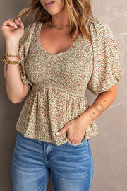 Floral smocked bodice peplum top with puff sleeves and a V-neck.