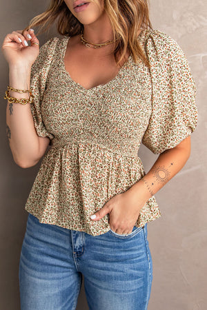 Floral smocked bodice peplum top with puff sleeves and a V-neck.