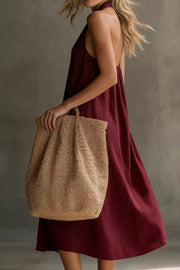 Burgundy halter midi dress with pockets, shown with a straw tote bag.