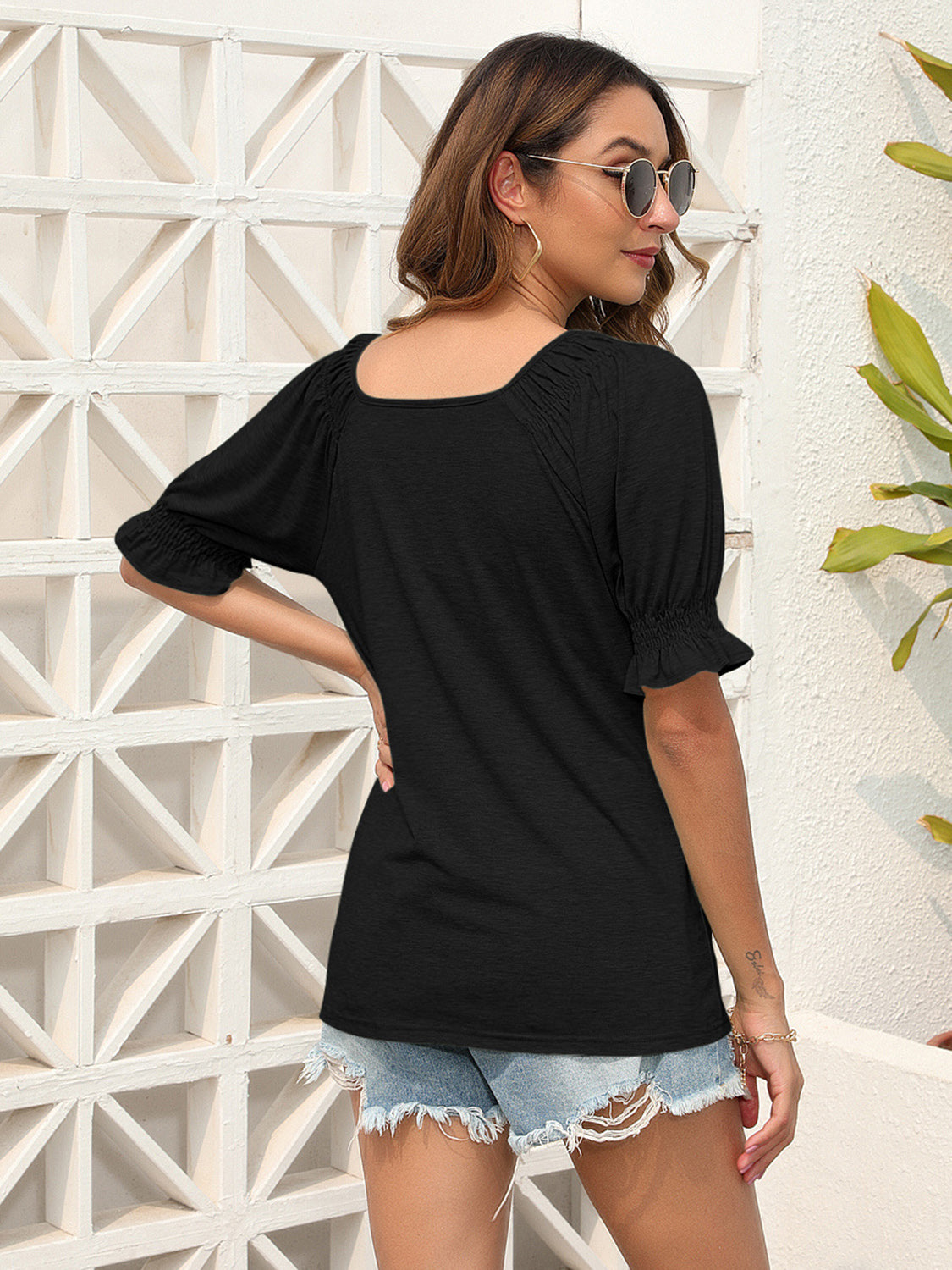 Black off-shoulder ruffled sleeve blouse with square neckline and smocked cuffs.