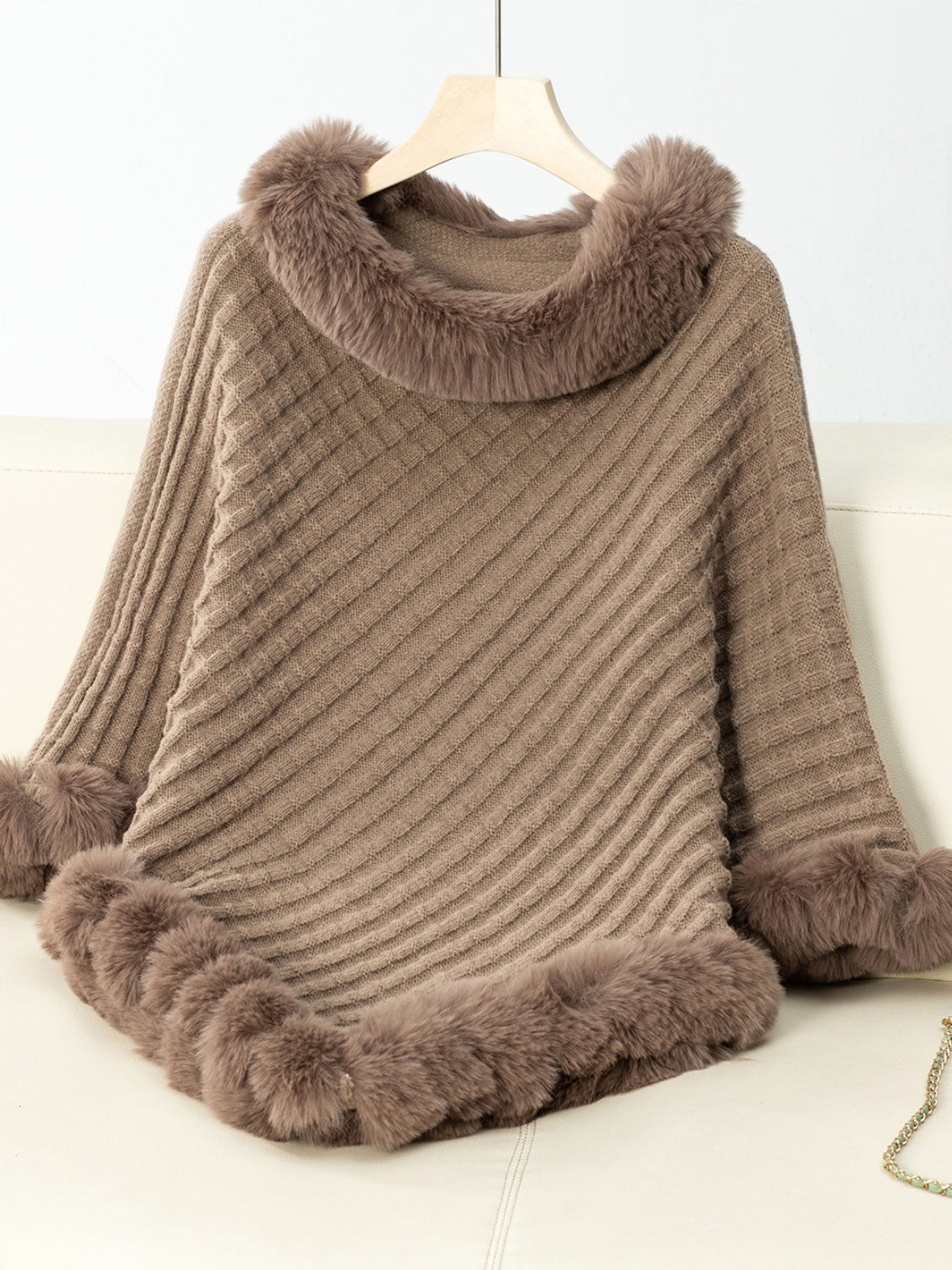 Camel knit poncho with diagonal ribbing and faux fur trim at neckline and hem.