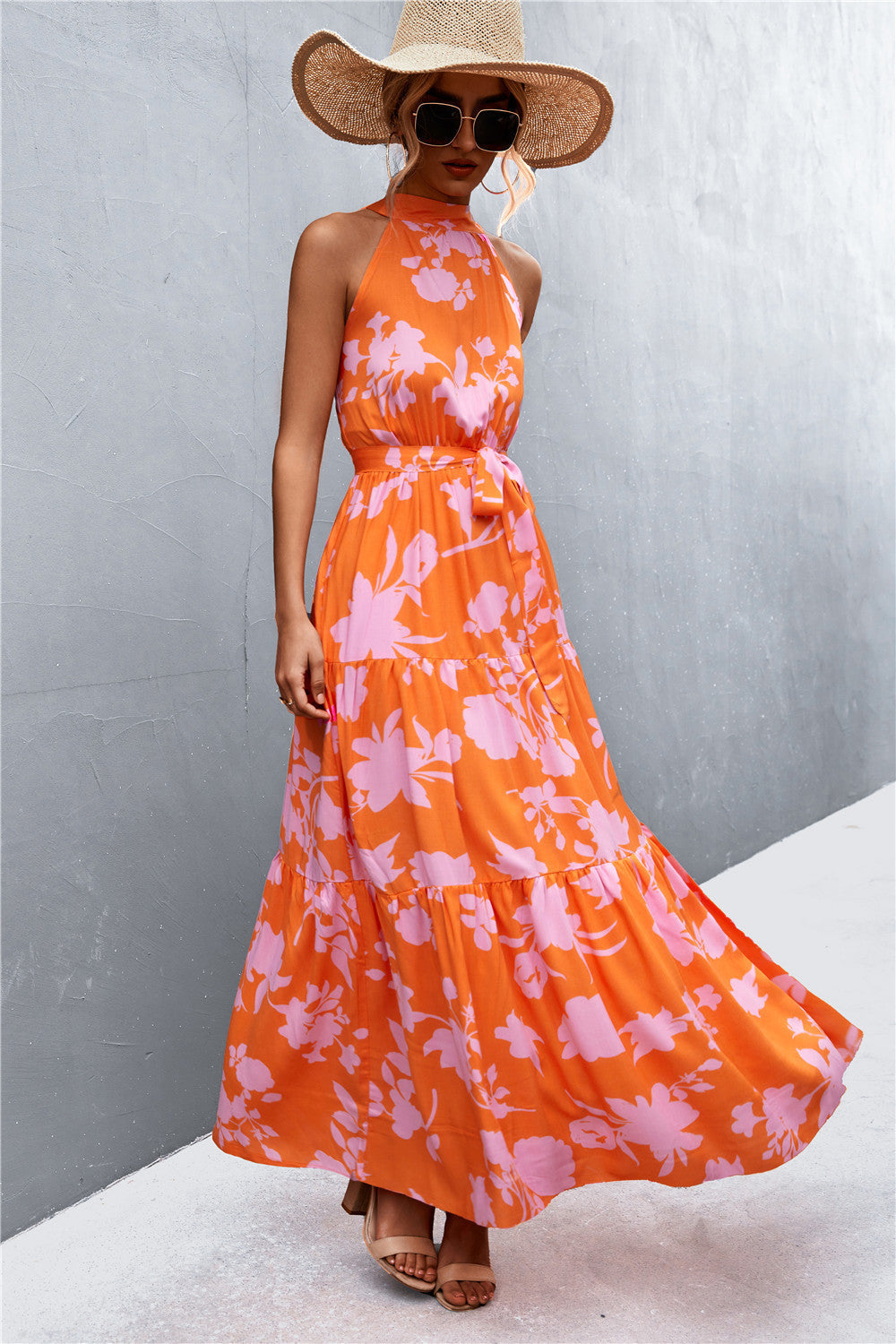 Orange floral print maxi dress with halter neckline and tiered skirt.
