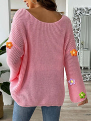 Pink knit sweater with embroidered floral details on the sleeves.