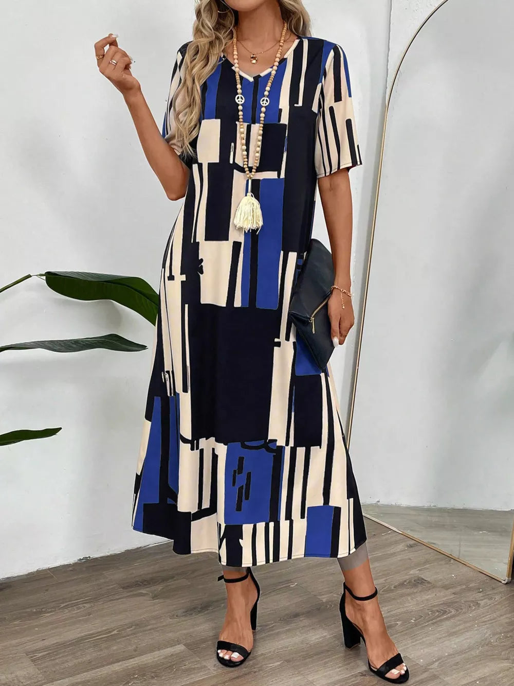 Geometric v-neck midi dress in dark blue, cream, and black abstract print with short sleeves.