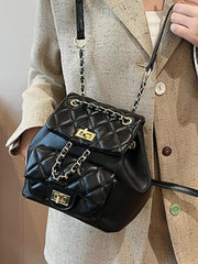 Black quilted mini backpack with gold chain straps and turn-lock closures.