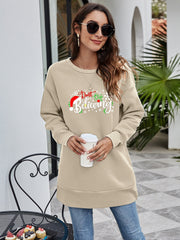 Beige graphic tunic sweatshirt with "Don't Stop Believing" holiday print and Santa hat detail.