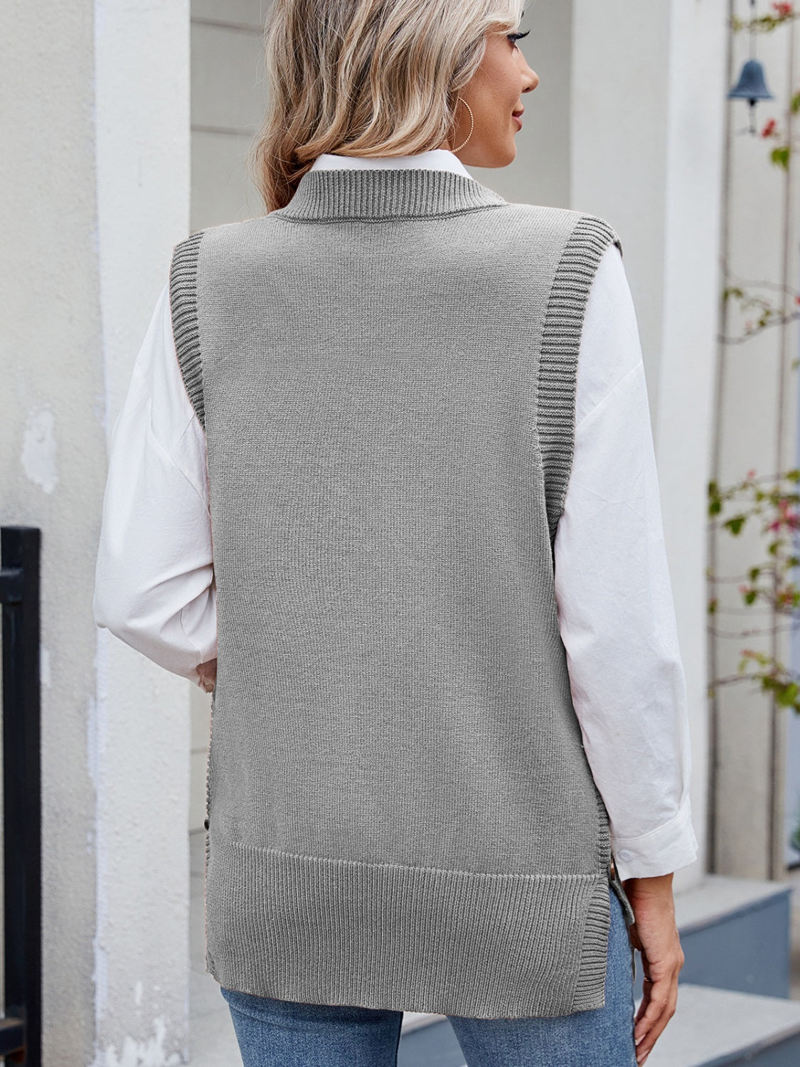 Gray ribbed knit vest with side buttons and collar detail, styled over a white shirt.