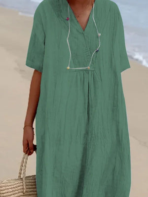 Green V-neck midi dress with short sleeves and textured fabric.