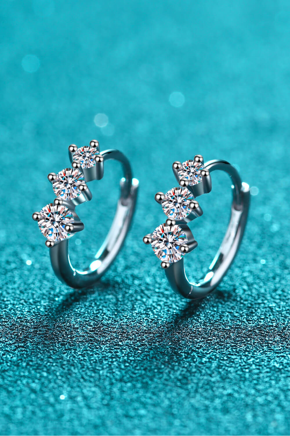 Silver triple stone cluster huggie earrings with clear cubic zirconia accents.