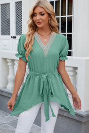 Green dotted swiss blouse with lace trim V-neck, short puff sleeves, belted waist, and asymmetric hem.