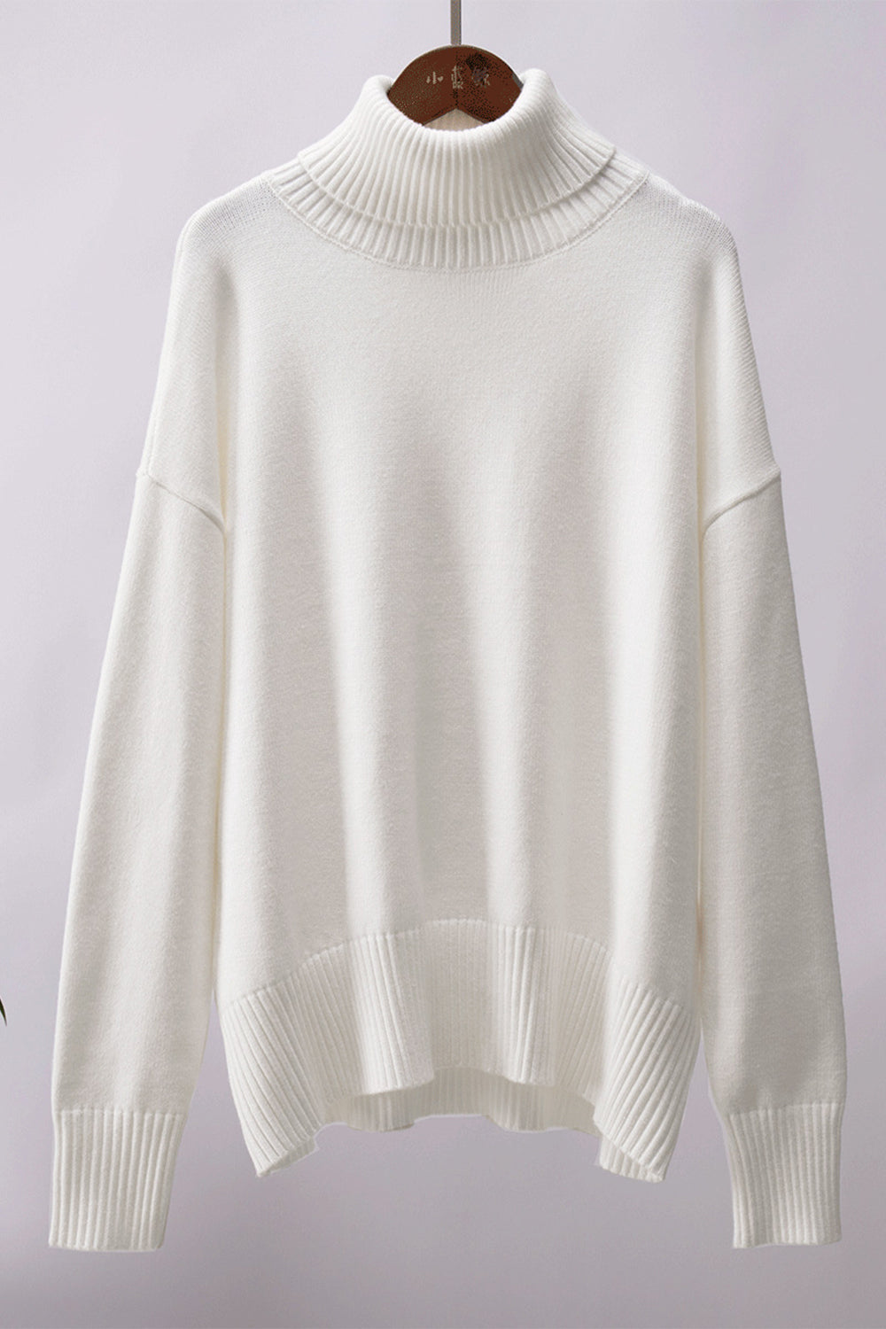 White relaxed roll-neck sweater with a boxy knit and ribbed details.