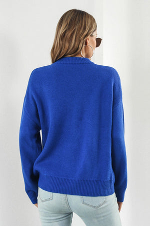 Royal blue acrylic sweater with a mock neck and intarsia smiley flower pattern.