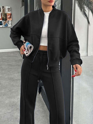 Black bomber jacket with wide-leg track pants, detailed with contrast stitching.