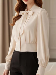 Apricot bow tie long sleeve button-down blouse with puff sleeves and a cinched waist.