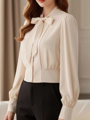 Apricot bow tie long sleeve button-down blouse with puff sleeves and a cinched waist.
