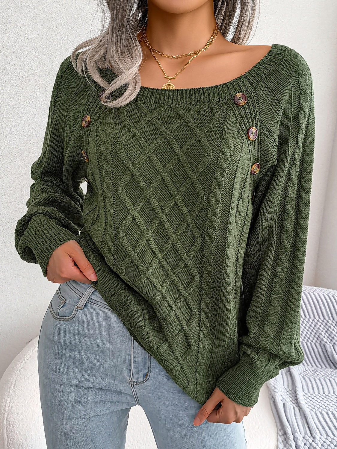 Army green cable-knit sweater with buttoned shoulder detail and a wide neckline.