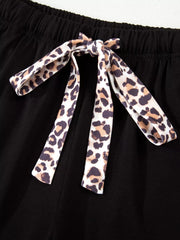Black pajama shorts with leopard print tie detail and elastic waistband.