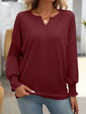 Burgundy textured blouson top with v-neck and smocked cuffs