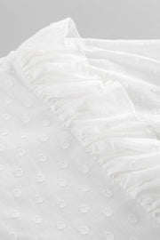 White textured shirt with ruffle trim and dot pattern detail