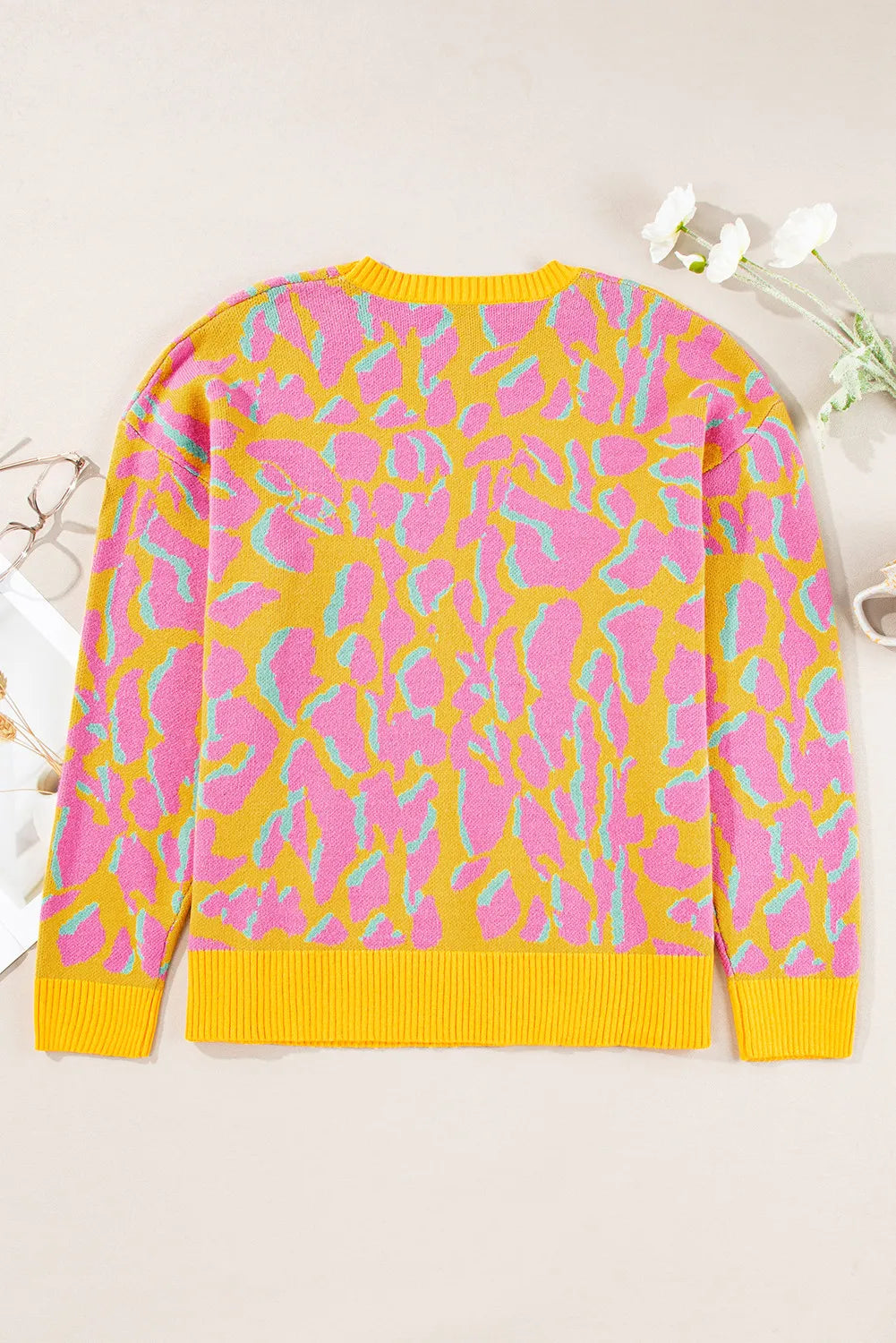 Women's crew knit sweater with abstract leopard print in fuchsia pink and mint green on yellow.