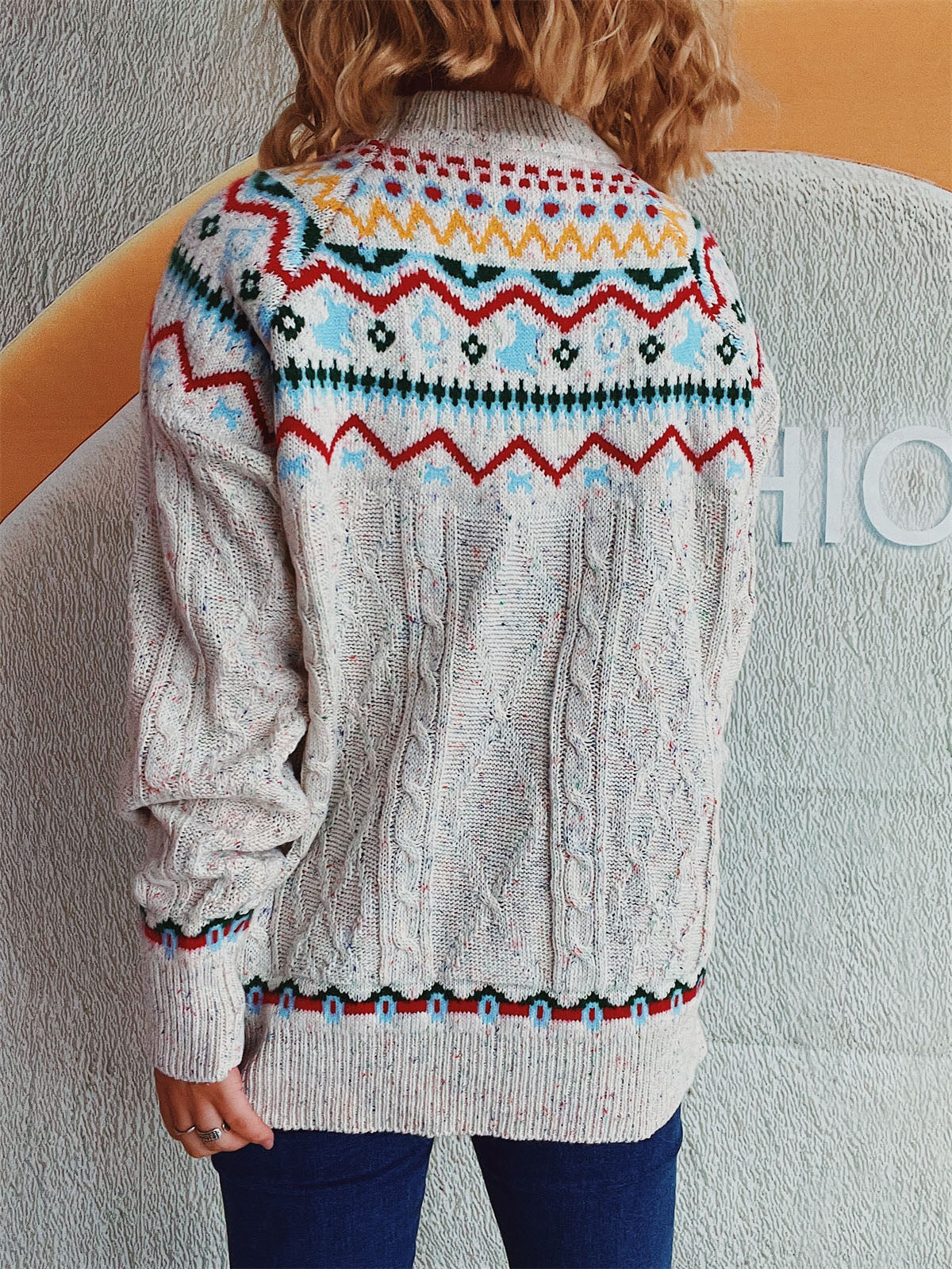 Beige cable knit turtleneck sweater with Fair Isle pattern and speckles.