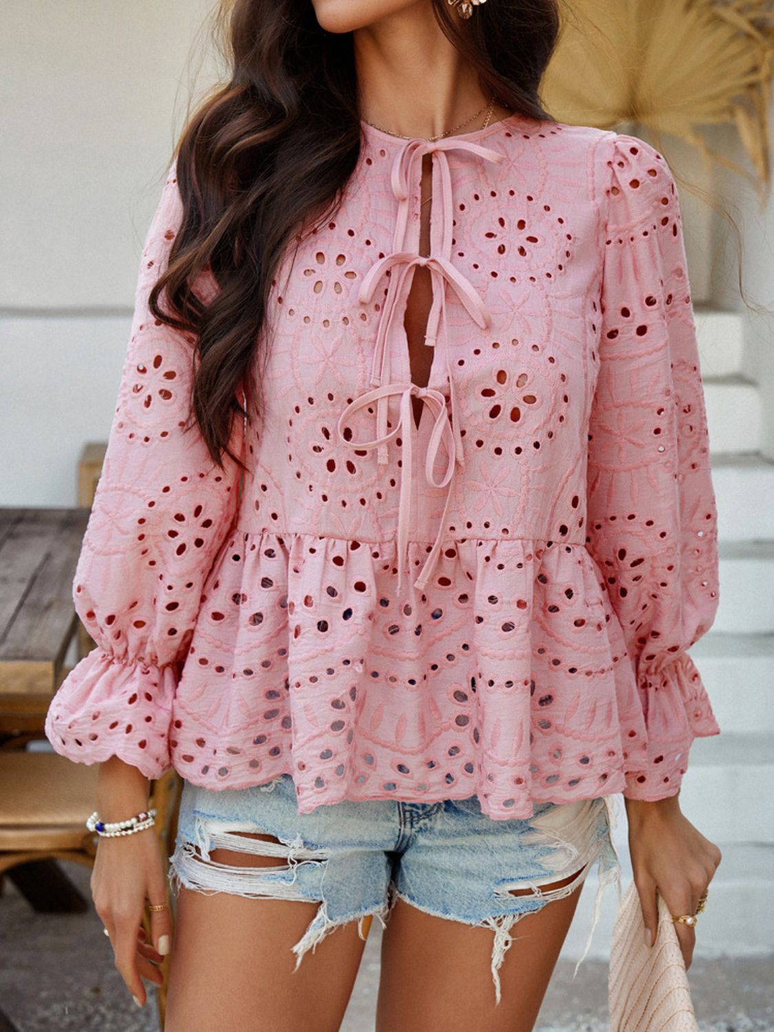 Dusty pink eyelet embroidered peplum blouse with tie neck and ruffled sleeves.