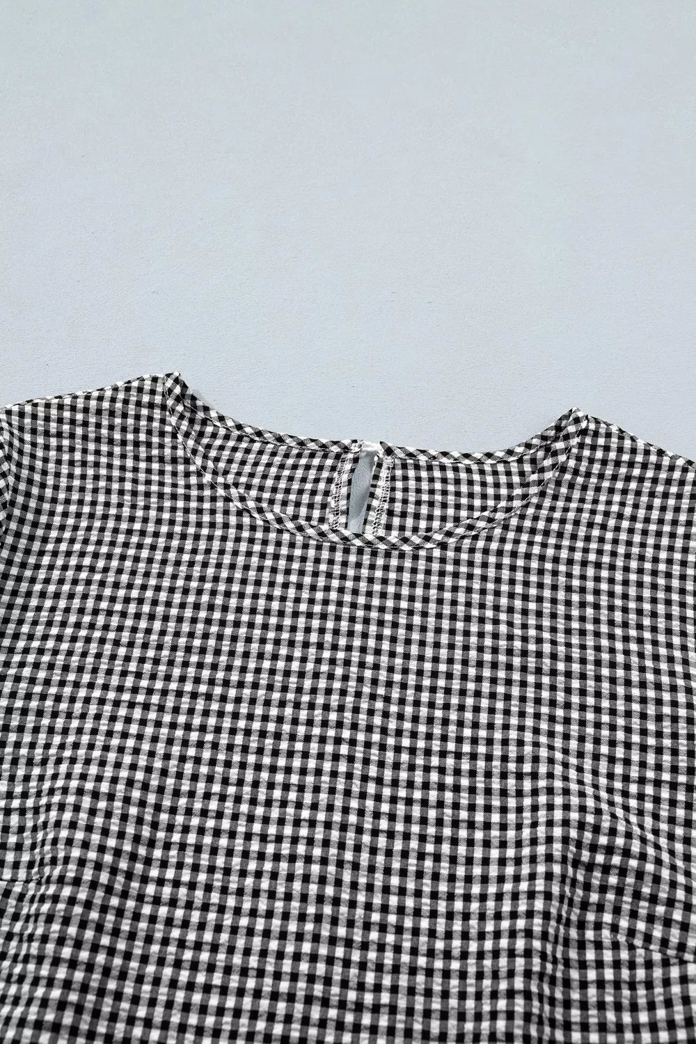 Black and white gingham polyester shirt with ruffled detail and keyhole back.