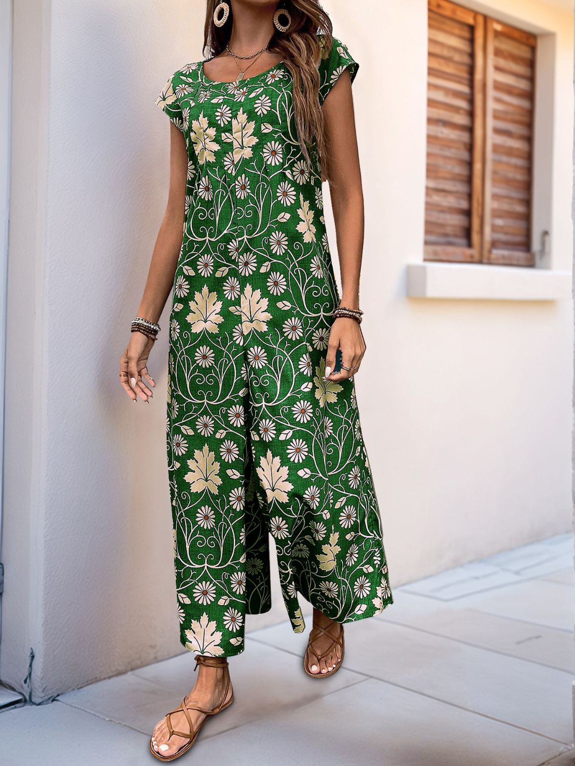 Dark green botanical print culotte jumpsuit with short sleeves and a scoop neck.