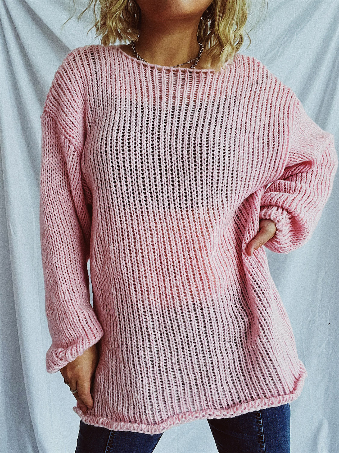 Blush pink open-knit acrylic boatneck pullover sweater with slouchy fit and long sleeves.