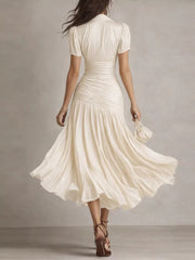 Beige ruched midi dress with pleated skirt and short sleeves.