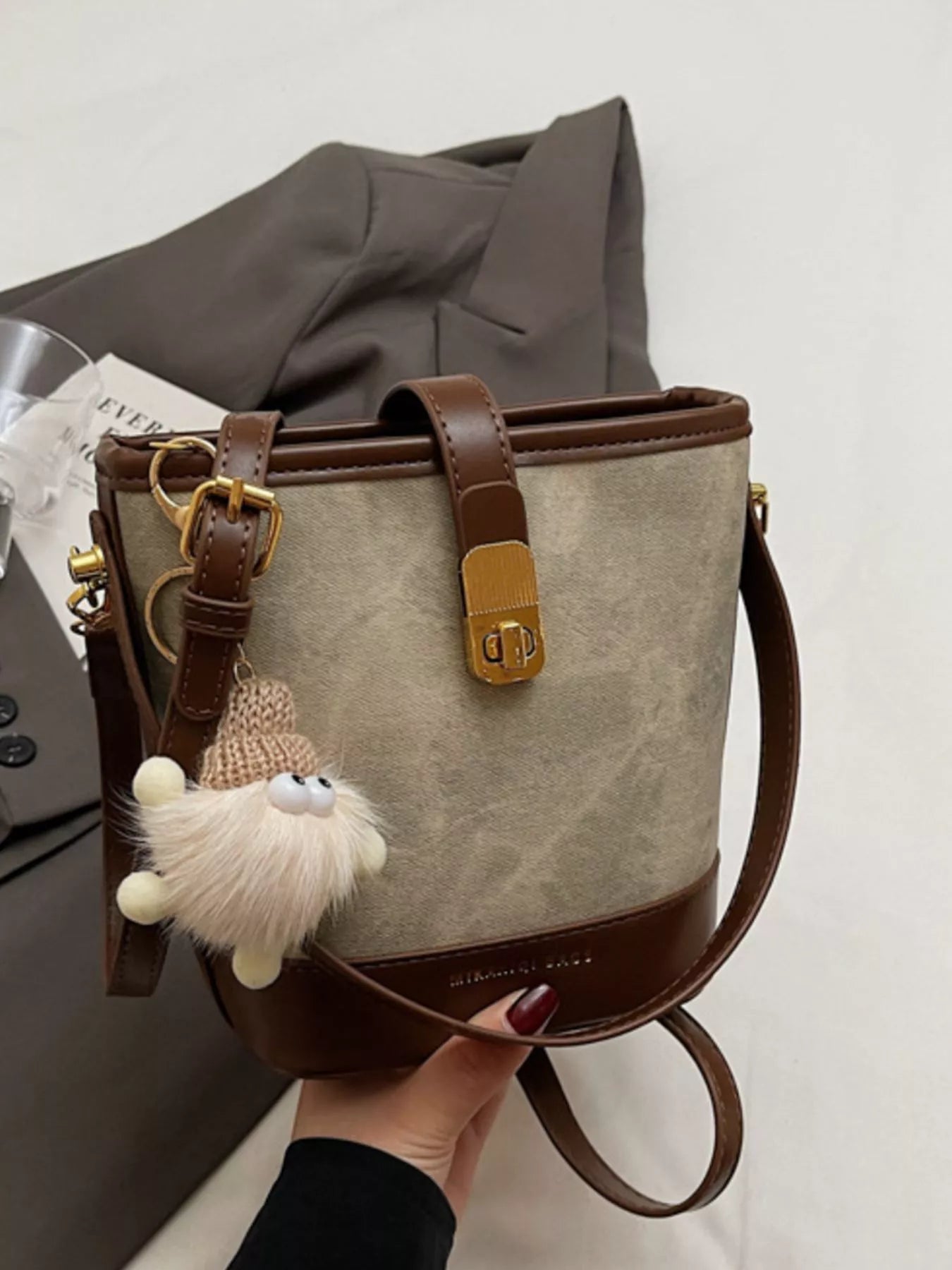 Elegant bucket bag in tan canvas with dark brown PU leather trim and a cute fuzzy charm.