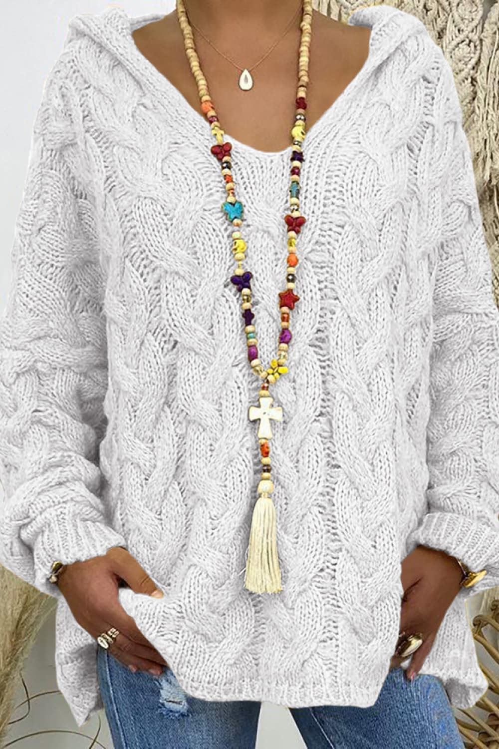 White cable knit hooded cocoon sweater with V-neck and long sleeves.