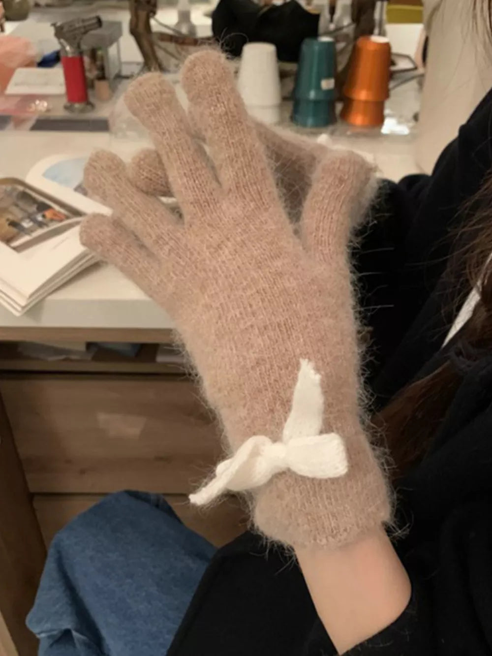 Khaki rabbit fur gloves with white bow detail.