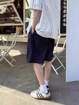 Navy blue relaxed fit chino shorts with pockets, styled with a striped shirt and sneakers.