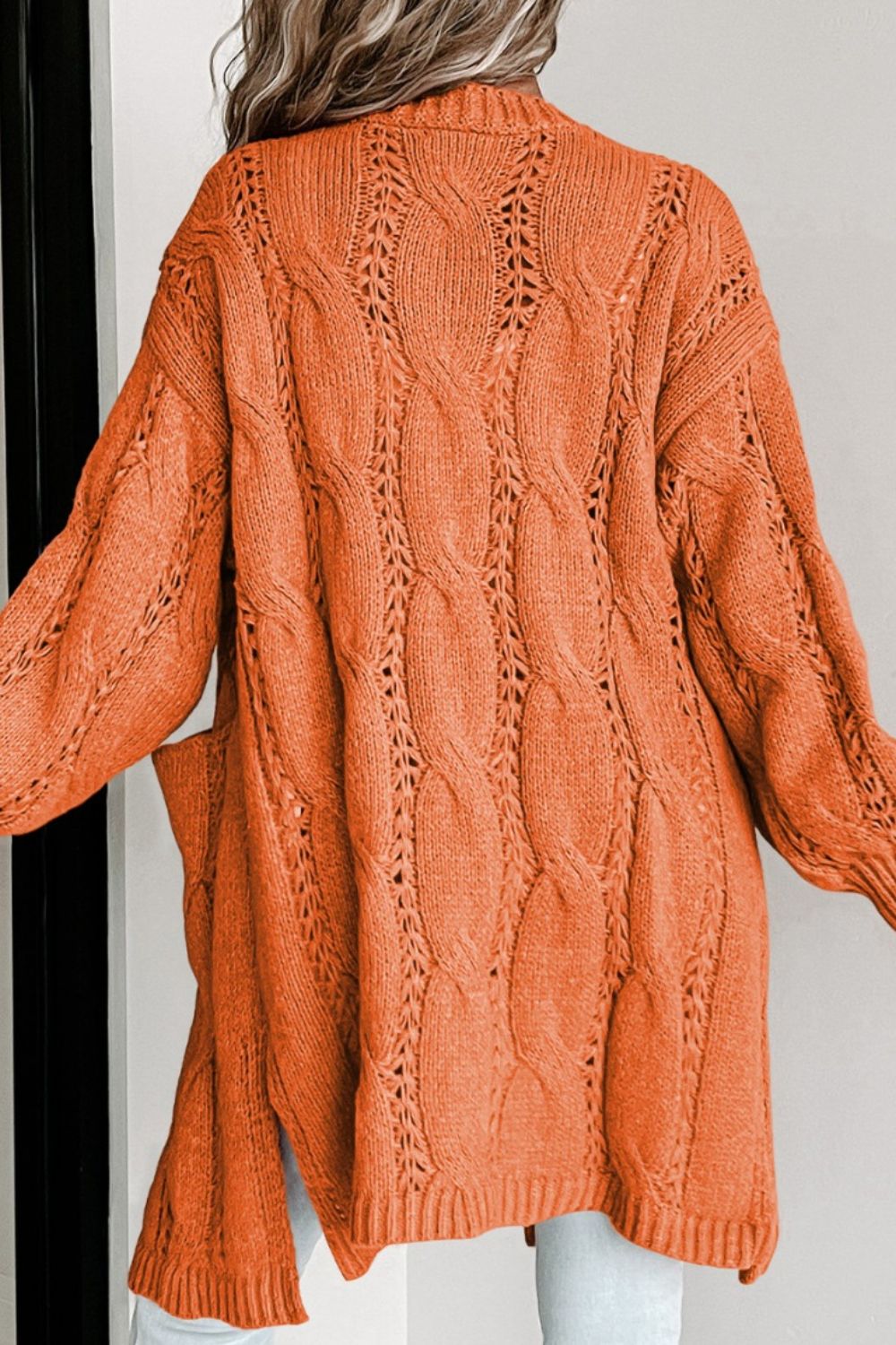Burnt Coral cable knit open-front cardigan with pockets and openwork details.
