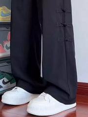 Black wide-leg sweatpants with tassel-accented side closures.