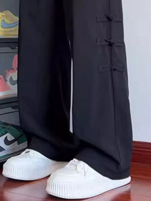 Black wide-leg sweatpants with tassel-accented side closures.