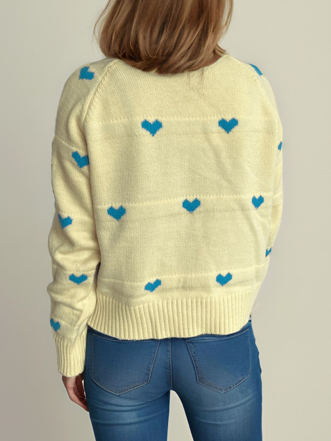 Pastel yellow knit sweater with blue heart pattern and ribbed trim.