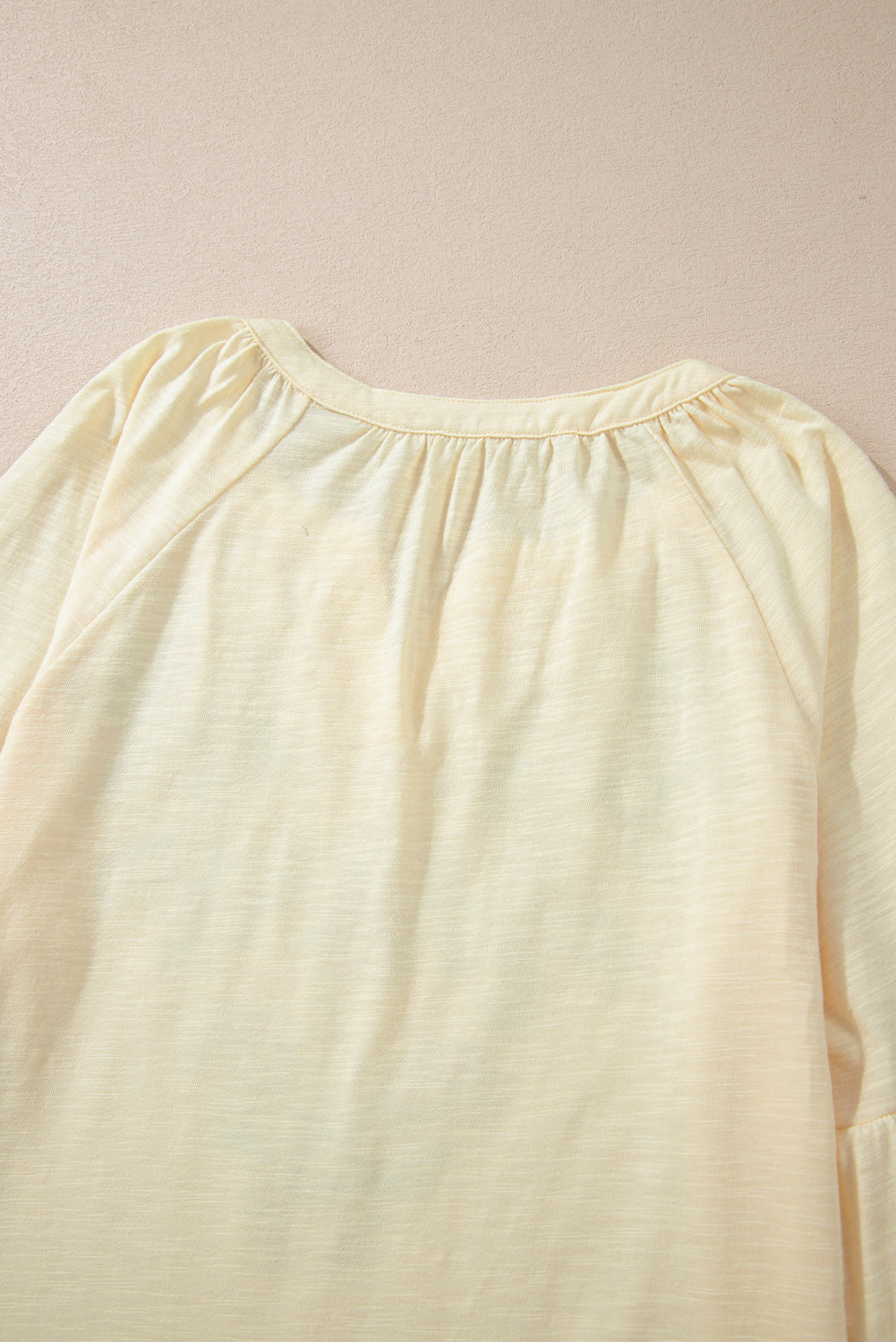 Pastel yellow blouse with gathered neckline and raglan sleeves.