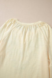 Pastel yellow blouse with gathered neckline and raglan sleeves.