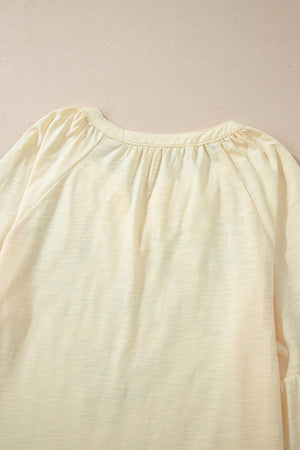 Pastel yellow blouse with gathered neckline and raglan sleeves.